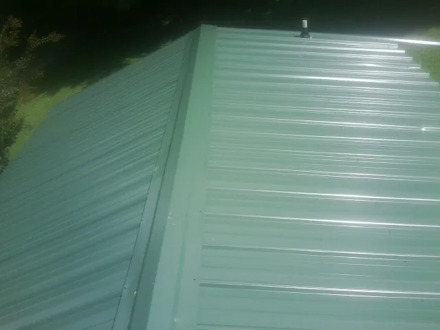 New green metal panels meeting at the ridge of a roof — Flat Roof Repair work by our crew in Burnet