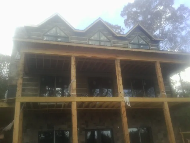 Dormers and porch framing on a large log home under construction — Roof Coating work by our crew in Burnet