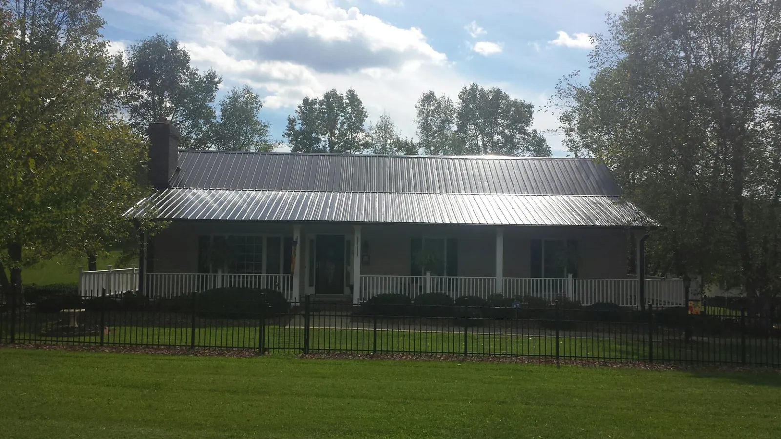 Gray metal roof on a brick ranch with a full width front porch — Gutter Guard Installation work by our crew in Burnet