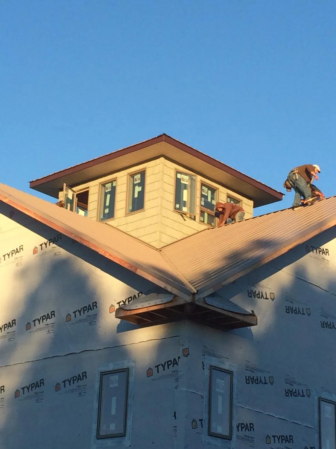 Roofers working around a rooftop cupola on a new metal roof at sunset — Roof Waterproofing in Burnet by Roofing Brothers